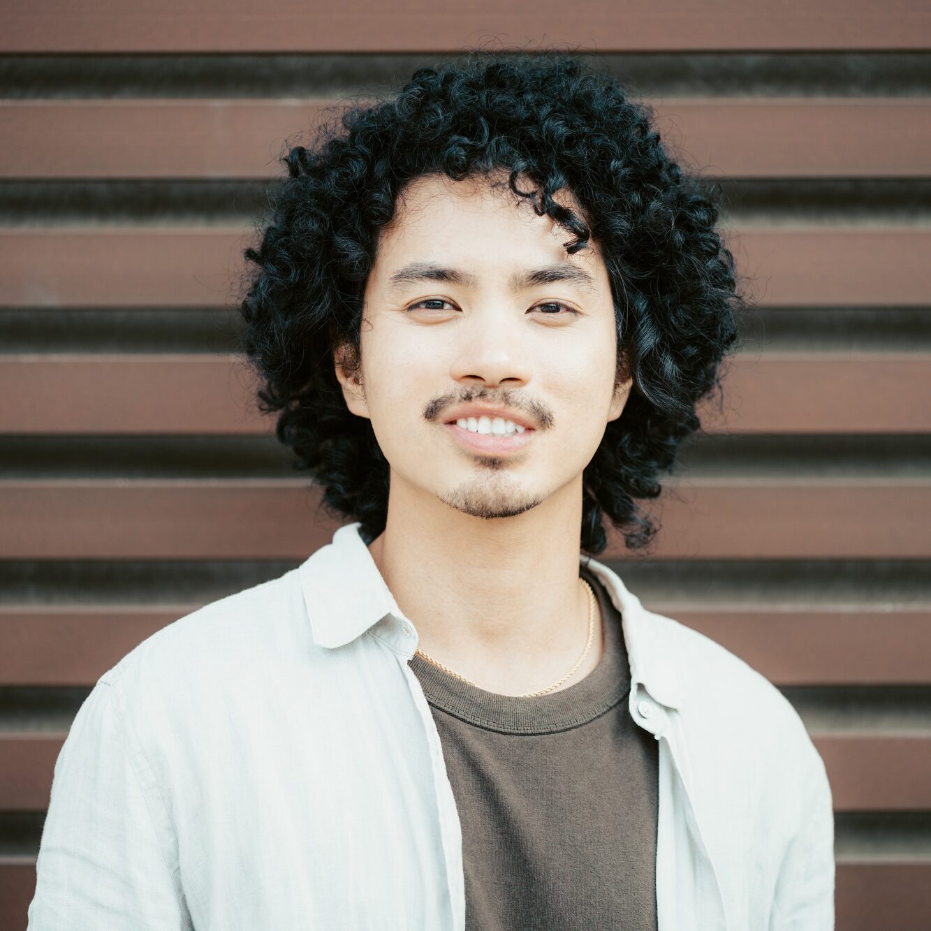 Curly-haired guy smiling subtly